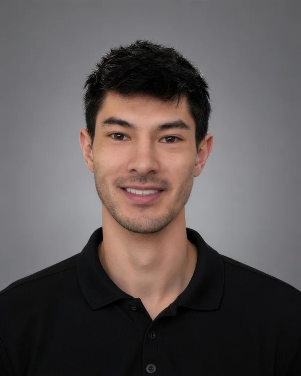 Evan Curole smiling, in a black polo shirt against a gray backdrop
