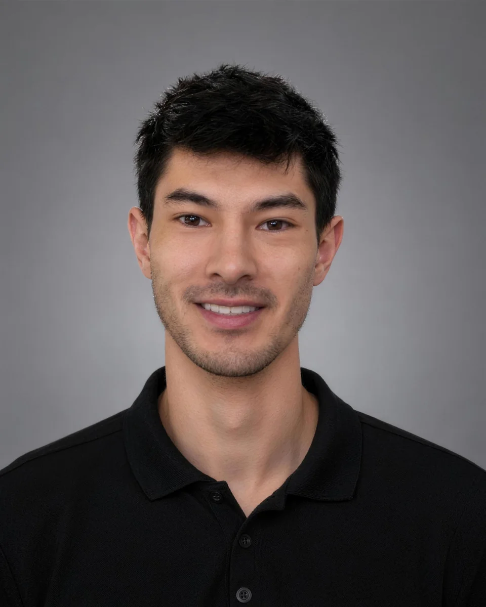 Evan Curole smiling, in a black polo shirt against a gray backdrop